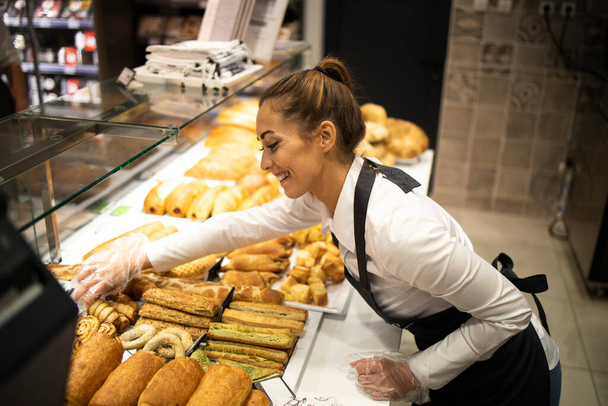Mujer preparando pastelería para la venta en el departamento de panadería de supermercados. - Foto, Imagen