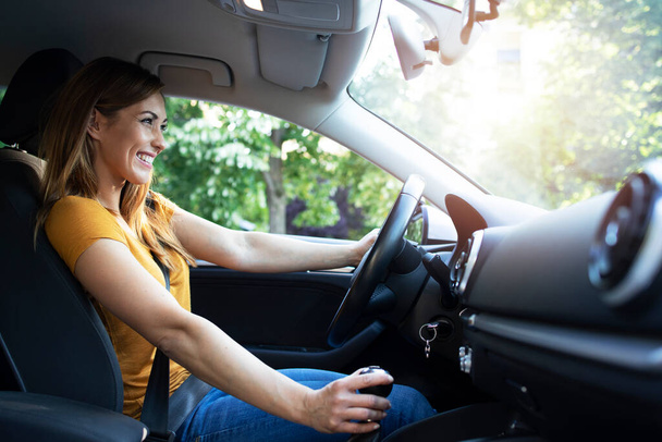 Auto interieur uitzicht van vrouwelijke bestuurder geniet van het besturen van een auto. Vrouw die auto rijdt. - Foto, afbeelding