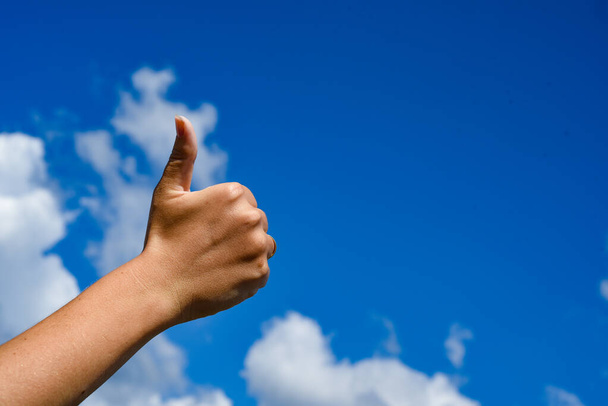 Thumb up in the sky. Hand show thumbs up on a blue sky - Foto, afbeelding