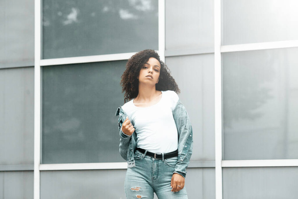 Mulatto black curly girl on street. Sunny summer city. Young woman denim style - Photo, image