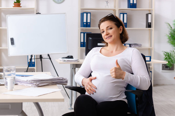 Old pregnant woman working in the office - Photo, Image