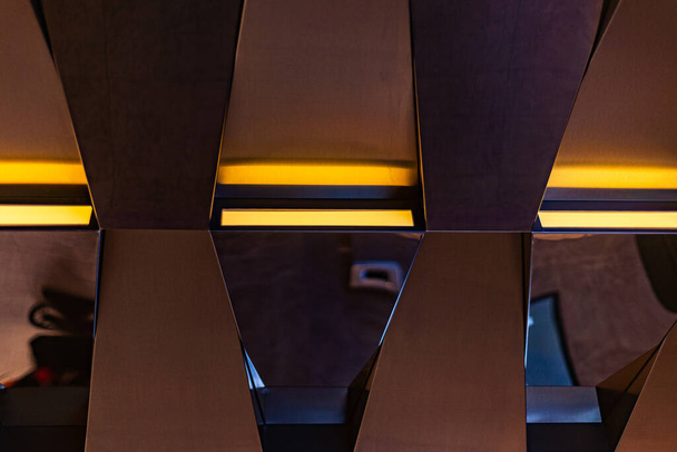 дизайн интерьера в оттенках коричневого: стены или потолок чередующихся балок с желтой подсветкой - Фото, изображение