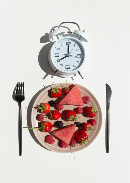 Intermittent fasting concept with empty colorful plates. On plate are berries, strawberries, raspberries, blackberries.Time to lose weight , eating control or time to diet concept. Top view. - Photo, Image