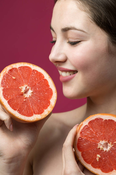 Portrait of an attractive girl holding a sliced slice of grapefruit - Fotó, kép