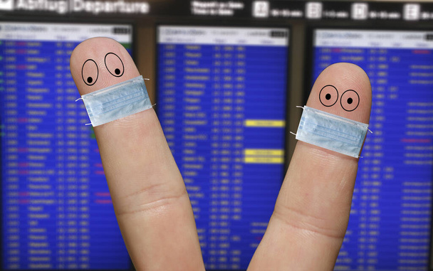 Zwei Fingergesichter mit Masken, die vor dem Flugplan soziale Distanz wahren - Foto, Bild