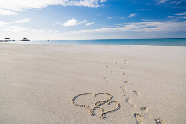 Herzen auf dem Sand am Strand gezeichnet. Zwei Herzen an einem Sandstrand am Meer gezeichnet, Romantik, Flitterwochen oder Hochzeitsthema in tropischer Strandlandschaft mit Kopierraum - Foto, Bild