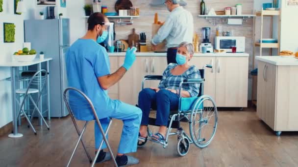 Ηλικιωμένοι ζευγάρι κατ 'οίκον επίσκεψη από γηριατρικό σε προστατευτική ενδυμασία - Πλάνα, βίντεο