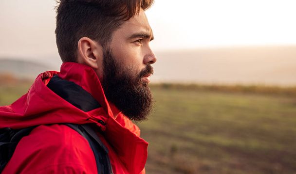 Serious bearded traveler standing in field - 写真・画像