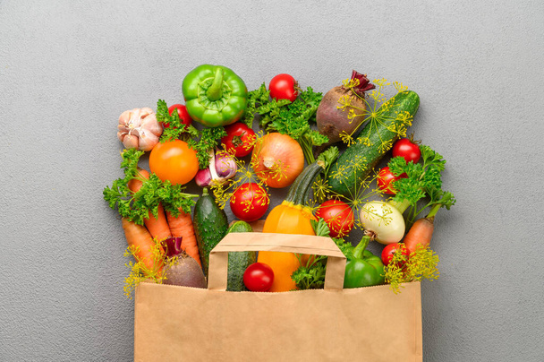 Paper bag of different vegetables on a gray background. - Photo, Image