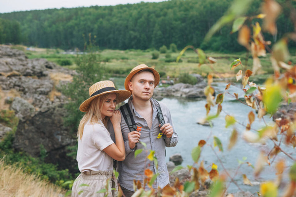 Jóvenes viajeros en pareja en trajes casuales en el fondo del río de montaña. Turismo local, concepto de viaje de fin de semana - Foto, imagen