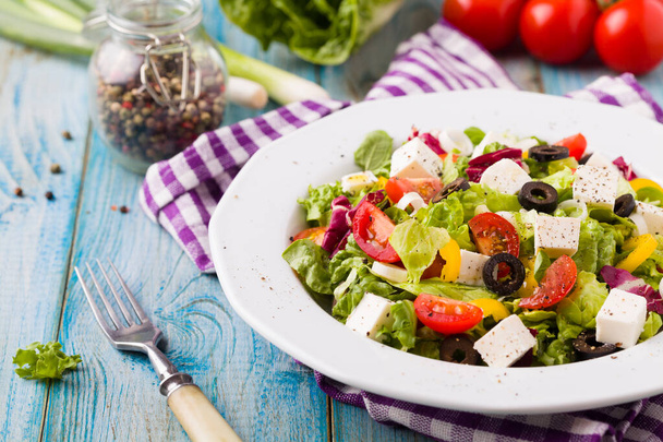 Fresh Greek salad on a plate. blue wooden board.  - Photo, image
