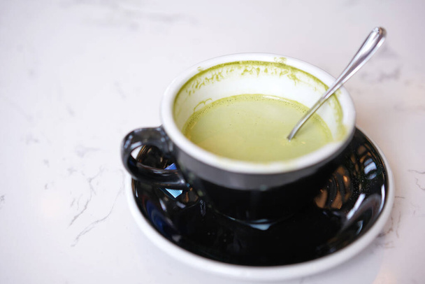Zielona herbata latte art, Matcha japoński z białą bitą śmietaną w czarnym kubku. Gorąca zielona herbata napój z serca latte sztuki mleka w kawiarni - Zdjęcie, obraz