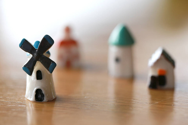 Маленький дом, крошечная ветряная мельница, маленькая башня в миниатюре, как деревенские игрушки на деревянном полу, в концепции совместного проживания идеи для экологически чистой энергии ветра - Фото, изображение