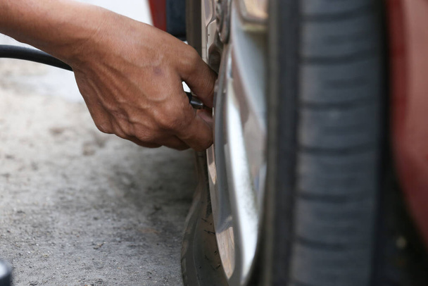 Plochá černá pneumatika automobilu při výměně pro opravu otvoru nebo nerovné pneumatiky auto na silnici - Fotografie, Obrázek