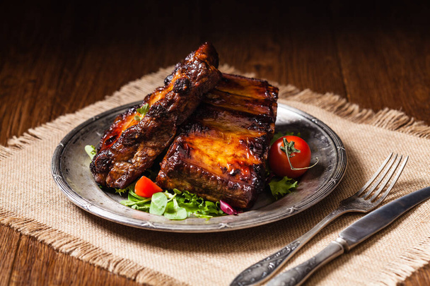 Roasted ribs, served on an old plate. Fron view. Dark or balck background. - 写真・画像