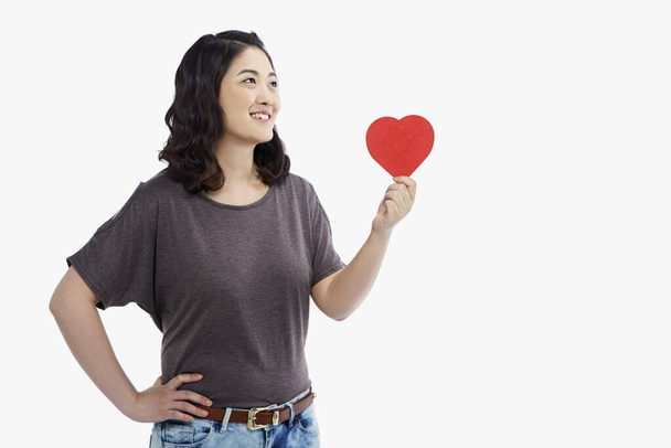 Cheerful woman holding up a red heart shape - Foto, Imagen