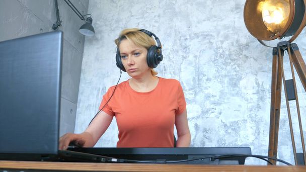 woman produces electronic music in the studio with a laptop and midi keyboard - Foto, imagen