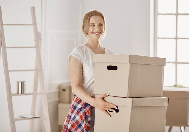 Красивая одинокая девушка распаковывает коробки и переезжает в новый дом - Фото, изображение
