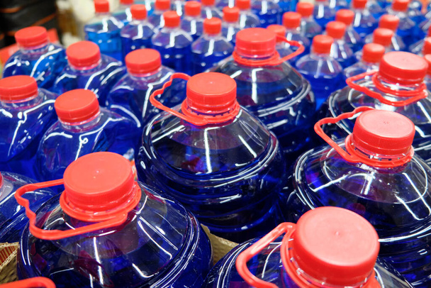 Dark blue fluid in the plastic bottles with red caps. - Foto, Imagem