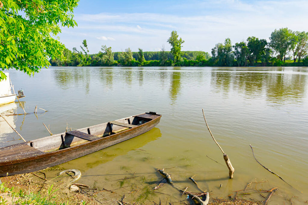 Vanha puinen kalastusvene ankkuroituna improvisoituun laituriin joella. - Valokuva, kuva