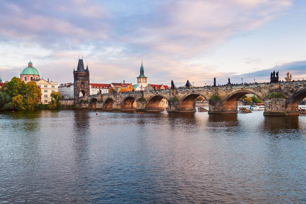Çek Cumhuriyeti Prag 'da gün batımında Vltava nehri boyunca uzanan Eski Şehir binaları ve Charles Köprüsü' nün güzel manzarası - Fotoğraf, Görsel