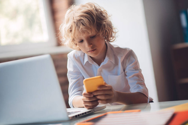 Cute blonde boy holding his smartphone and texting - Valokuva, kuva