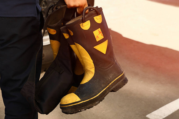 Bombero sostiene botas protectoras contra incendios de goma. - Foto, imagen