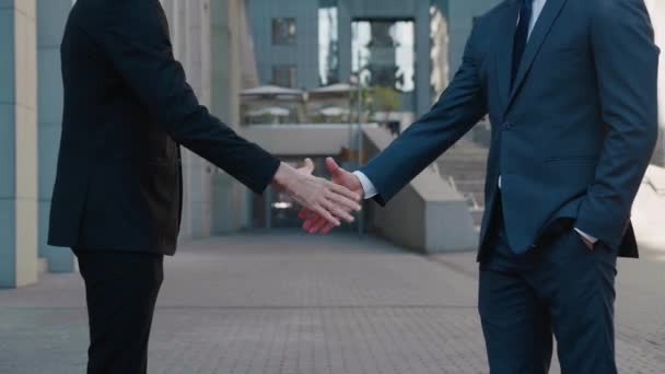 ビジネススーツのトップマネージャーの手を閉じて、ビジネスセンターの背景で互いに握手し、契約に同意します。誰も知らない. - 映像、動画