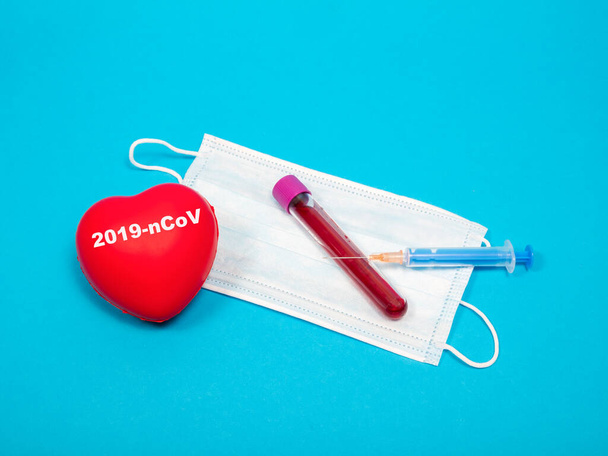 New coronavirus blood test(2019-nCoV), medical face mask, syringe and needle, test tube coronavirus blood test on blue background - Photo, Image