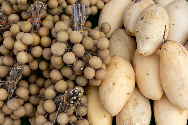 Longan and mango for sale on local street market in Thailand. Tropical fruits close up - Φωτογραφία, εικόνα