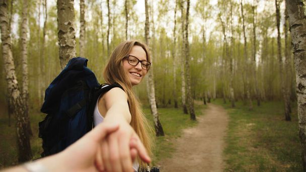 Hiker woman holding mans hand and leading him in forest. Couple in love. Point of view shot. - Fotoğraf, Görsel