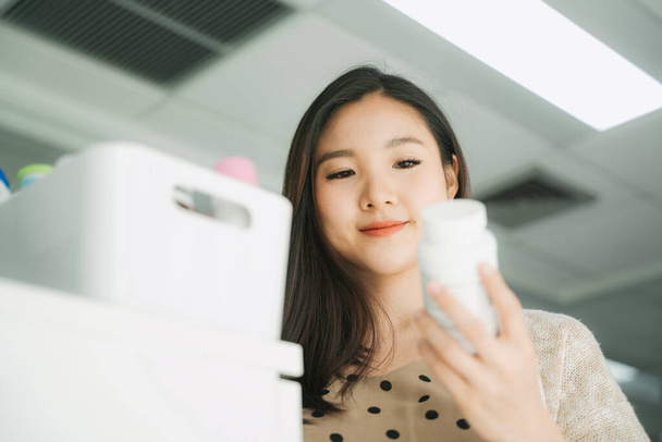 Krásná těhotná asijské businesswoman čtení štítek na lékařské sklenice láhev. - Fotografie, Obrázek