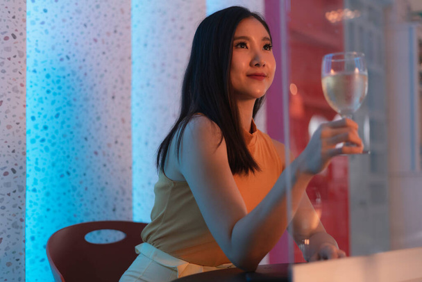 Hermosa tailandesa asiática sosteniendo copa de vino en club nocturno. - Foto, imagen