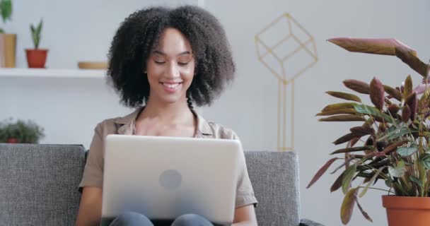 Young African American freelancer works remotely from home room, uses laptop to communicate with fellow clients, expresses support approval, answering video conference call, throws thumb up, like sign - 映像、動画