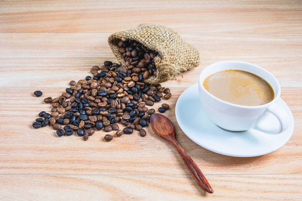 Кофейные чашки и жареные кофейные зерна на деревянном столе - Фото, изображение