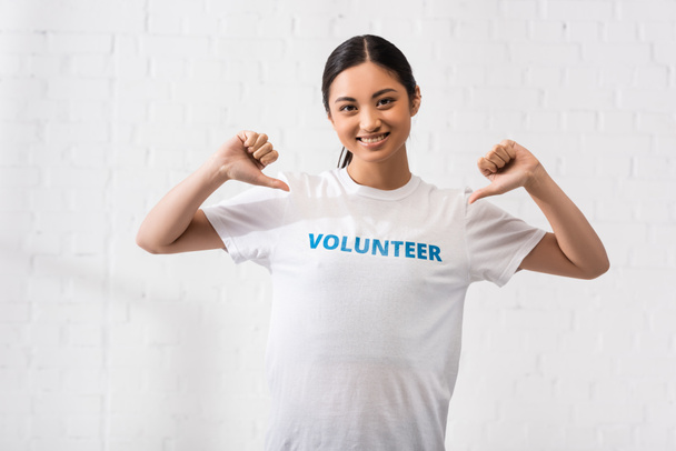 Volontari asiatici che puntano con le dita la scritta sulla t-shirt  - Foto, immagini