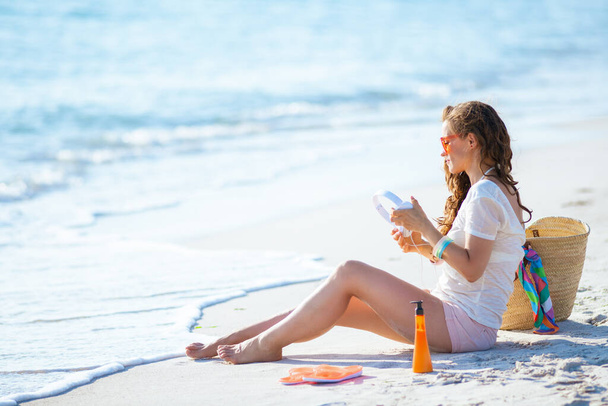 young woman in white t-shirt and pink shorts with headphones sitting on the seacoast. - Foto, imagen