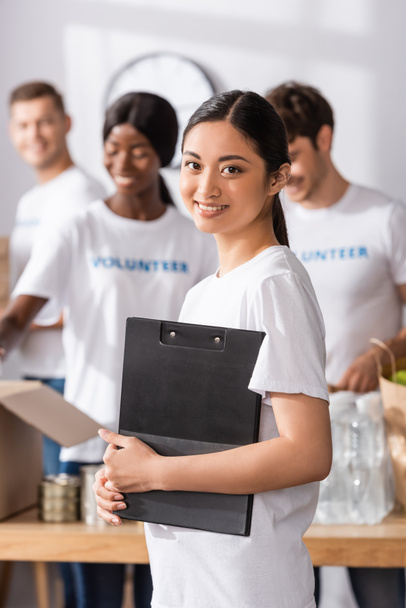 Selective focus of asian volunteer holding clipboard in charity center  - Photo, Image