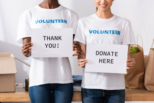 Cropped view of multiethnic volunteers holding cards with thank you and donate here lettering  - Foto, Imagem