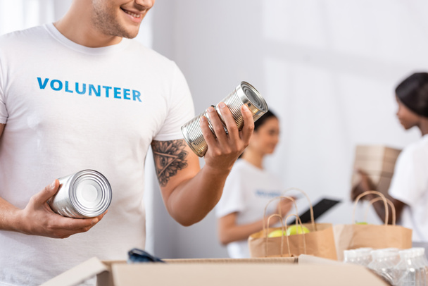 Önkéntesként konzervdobozokat tartó önkéntesek szelektív fókusza a jótékonysági központban  - Fotó, kép