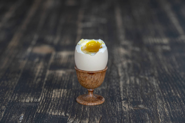 Soft boiled egg in eggcup on wooden table background, close up - Zdjęcie, obraz