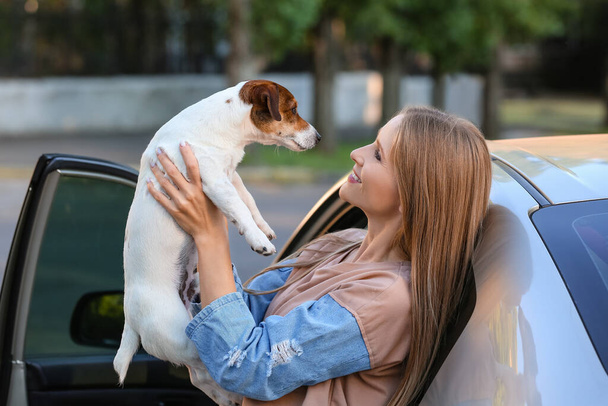 Vrouw met schattige hond in de buurt van moderne auto buiten - Foto, afbeelding