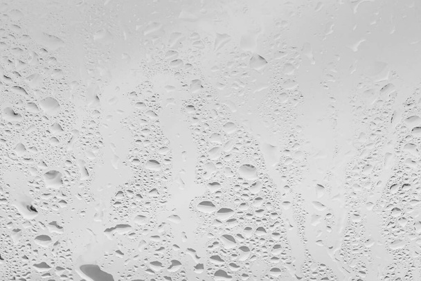Krople deszczu na powierzchni okularów okiennych z szarym tle nieba. Naturalne tło kropel deszczu. Abstrakcyjne nakładki na projekt. Koncepcja złej pogody deszczowej. - Zdjęcie, obraz