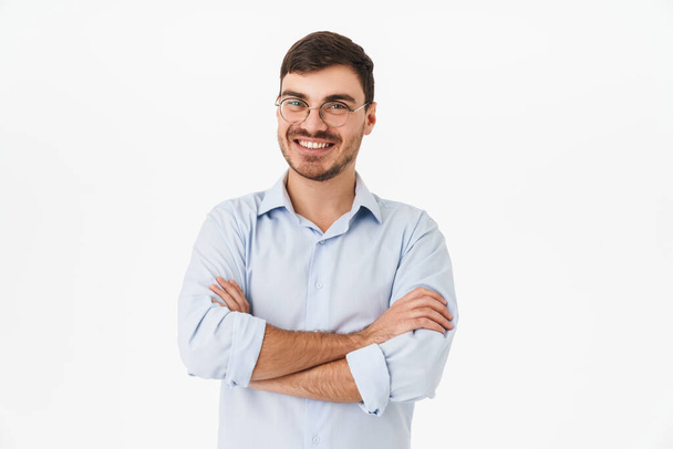 Photo of joyful young man in eyeglasses posing with hands crossed and smiling isolated over white background - Fotó, kép