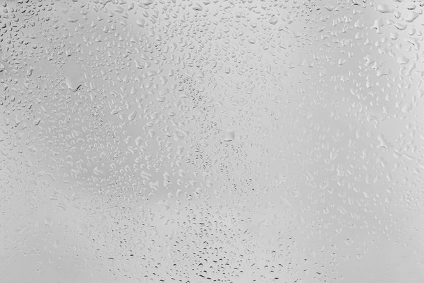 Dešťové kapky na povrchu okenních brýlí s šedou oblohou pozadí. Přirozené prostředí kapek deště. Abstraktní překrytí pro design. Koncept špatného deštivého počasí. - Fotografie, Obrázek