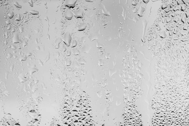 Gotas de lluvia en la superficie de los cristales de la ventana con fondo gris cielo. Fondo natural de gotas de lluvia. Superposición abstracta para el diseño. El concepto de mal tiempo lluvioso
. - Foto, Imagen