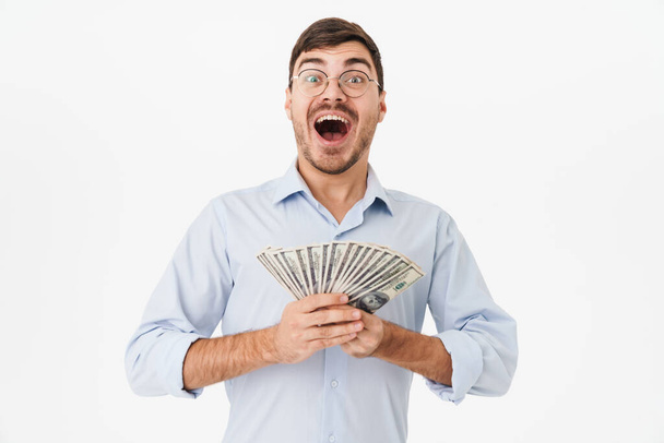 Photo of delighted man in eyeglasses holding dollars and expressing surprise isolated over white background - Φωτογραφία, εικόνα