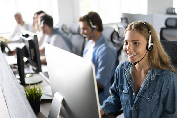 How can I help you Beautiful call center workers in headphones are working at modern office - Foto, imagen