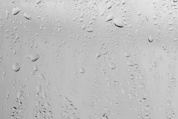 Σταγόνες βροχής σε γυάλινα παράθυρα επιφάνεια με γκρι φόντο του ουρανού. Φυσικό σκηνικό από σταγόνες βροχής. Αφηρημένη επικάλυψη για το σχεδιασμό. Η έννοια της κακοκαιρίας. - Φωτογραφία, εικόνα
