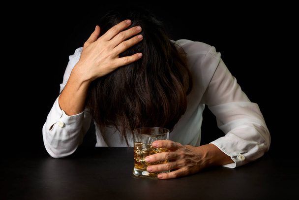 Mujer que ha abusado del alcohol con un vaso de whisky y hielo. Concepto de problemas sociales - Foto, imagen